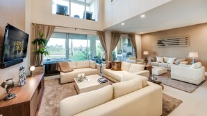 Uma sala de estar ampla, com pé direito alto, grandes janelas e design de interiores moderno.