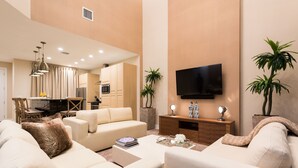 A modern living room with a sofa, coffee table, and TV. There is a kitchen in the background. - Gorgeous 3BDHome/Near Disney/No Fees/Free Parking/Wi-Fi/BBQ Grill/Shared Pool (Kissimmee)