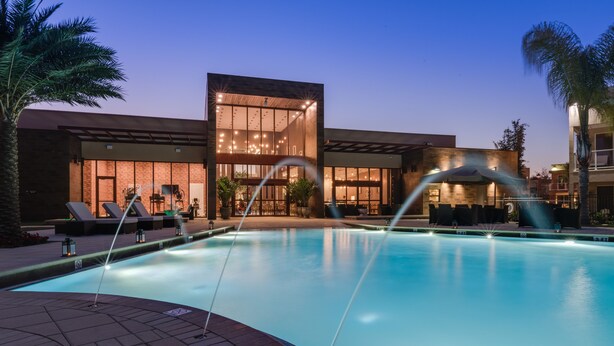 A modern pool area with a clear view of the pool, lounge chairs, and a building with large windows. - Gorgeous 3BDHome/Near Disney/No Fees/Free Parking/Wi-Fi/BBQ Grill/Shared Pool (Kissimmee)