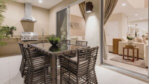 A modern kitchen with a dining area, featuring a grill, a large window, and a cozy living room with a sofa and decorative plants. - Near Disney/Gorgeous home/ Parking/ BBQ Shared Heated Pool (Kissimmee)