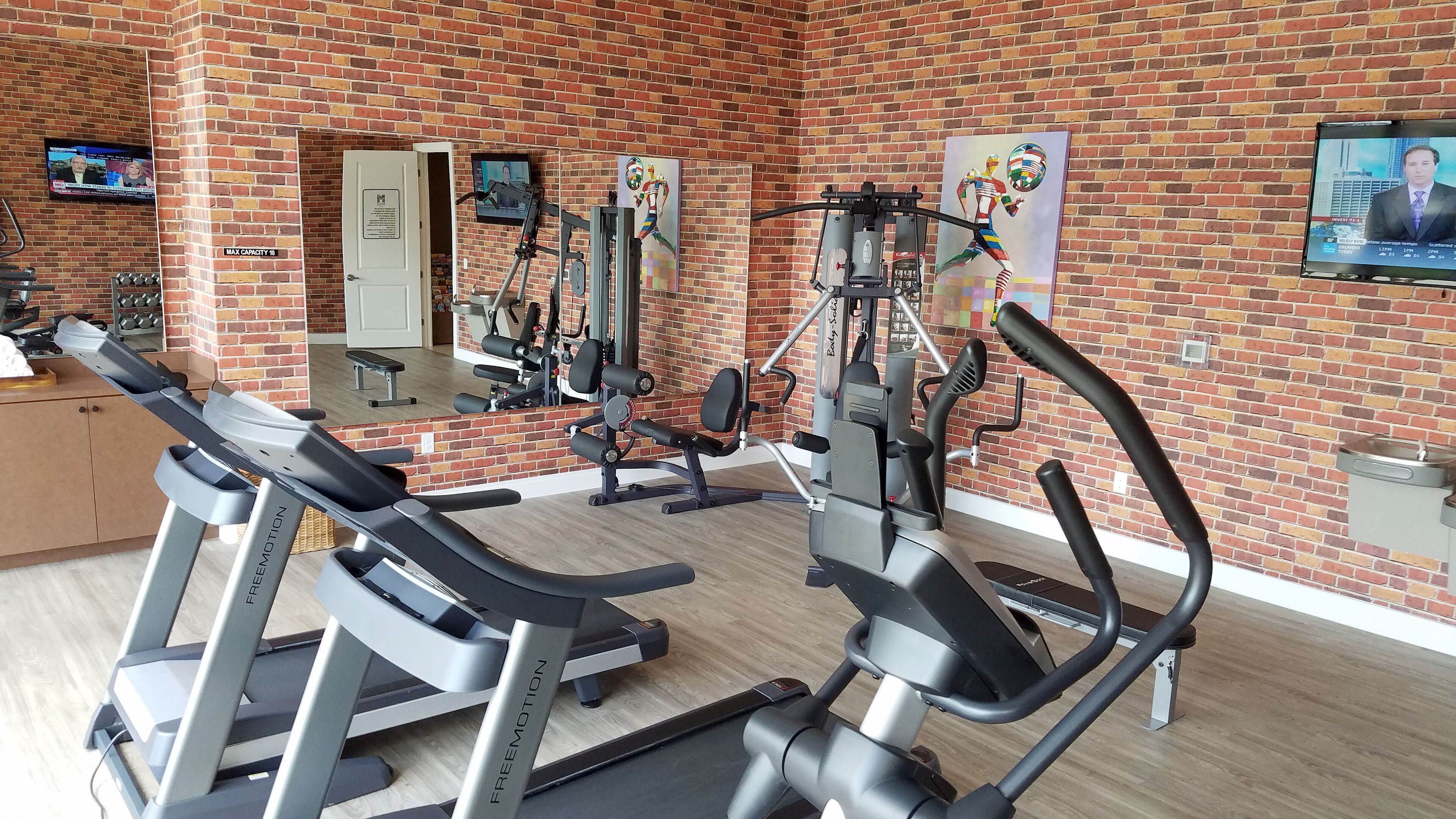 A gym with exercise equipment, a mirror, and a brick wall.
