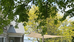 Un patio amueblado con mobiliario exterior y una p érgola que da sombra, con vistas a una masa de agua.