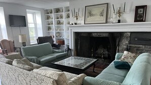 Una sala de estar con chimenea, televisor y estantería.