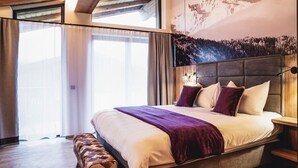 Un dormitorio moderno con una cama grande, un banco y un mural de montañas en la pared.