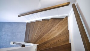 A staircase with wooden steps and white handrails, leading to a landing area with a light fixture. - Vacation cottage on the dike (Büsum)