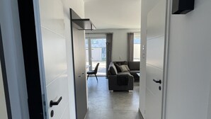 A modern hotel corridor with a grey tiled floor, white walls, and a grey sofa set in the background. - Vacation cottage on the dike (Büsum)