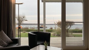 Moderni olohuone, jossa on suuri liukuovi, joka johtaa terassille, jolta avautuu näkymä vesistöön.