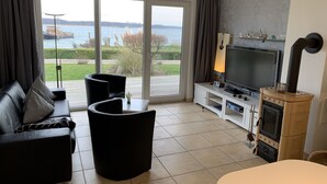 Olohuone, jossa on sohva, nojatuoleja, televisio ja takka.