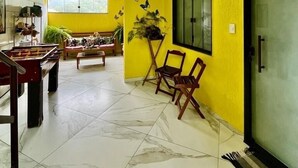 A bright yellow room with a foosball table, a large window, and a glass door. - Pousada Ohana Paraty  (Paraty)
