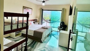A hotel room with a bunk bed, a desk, a chair, a ceiling fan, and a view of the ocean. - Pousada Ohana Paraty  (Paraty)