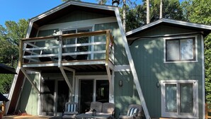 A two-story house with a deck, outdoor seating, and a large window. - Riverfront Cabin – Summertime Escape in the Shenandoah Valley (Shenandoah)