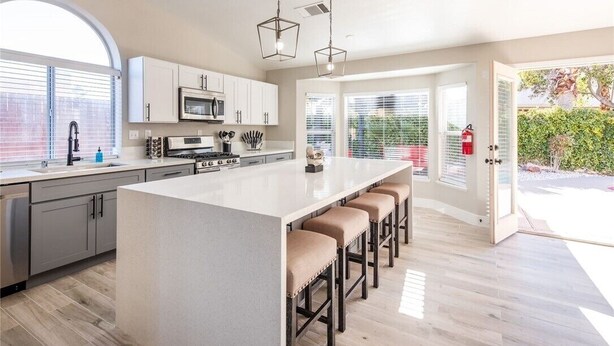 A modern kitchen with a large island, bar stools, and a view of the outdoors. - Modern and Bright Resort Style Home w/Heated Pool (Las Vegas)