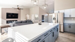 A modern kitchen with a large island, grey cabinets, and stainless steel appliances. - Modern and Bright Resort Style Home w/Heated Pool (Las Vegas)
