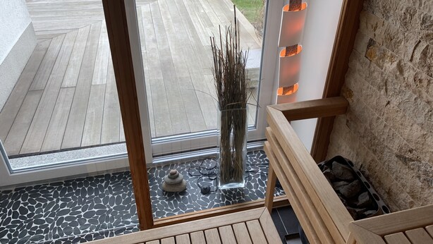 Ein modernes Interieur mit einer Holztreppe, einer Glastür zum Außenbereich und einer Steinwand.