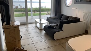 Ein modernes Wohnzimmer mit einer Couch, einem Couchtisch und Blick auf ein Gewässer durch große Fenster.
