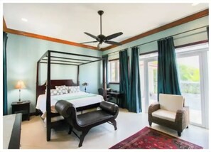 Relax in a serene bedroom with a four-poster bed, ceiling fan, and large window.