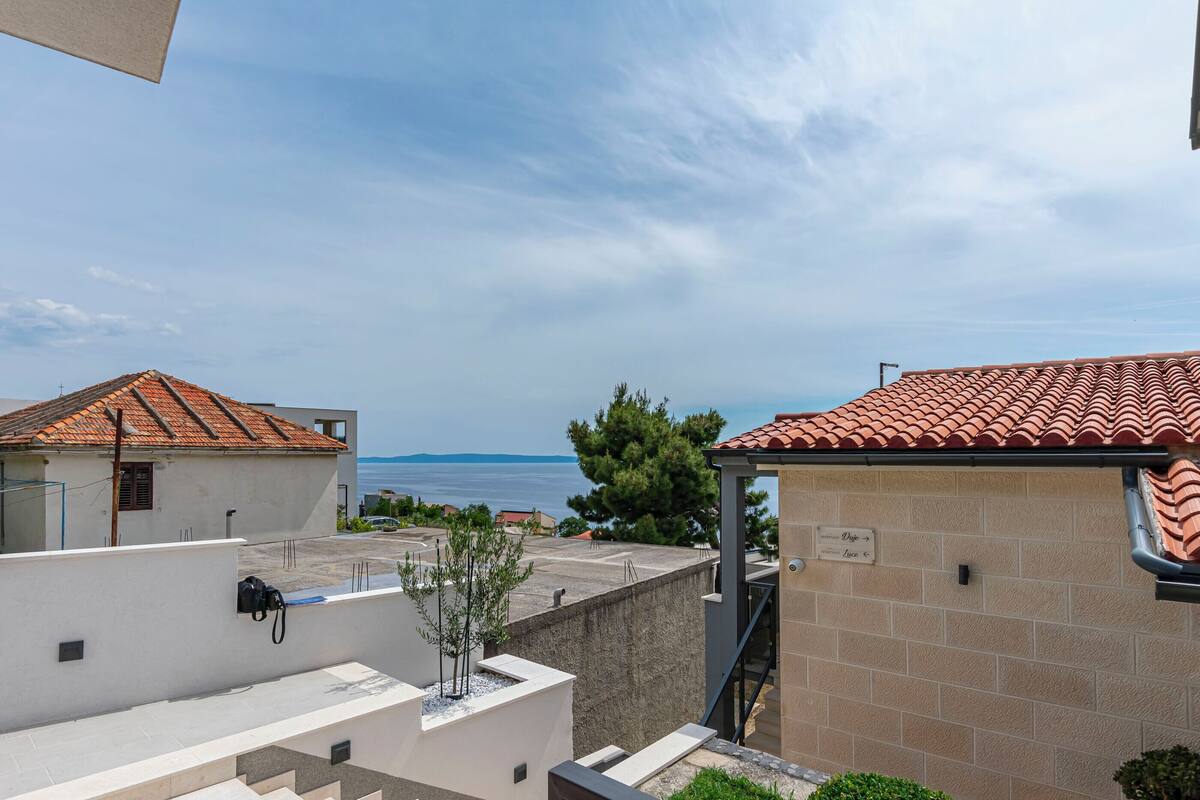 Un quartier résidentiel offrant une vue sur la mer, avec des bâtiments aux toits de tuiles rouges et un escalier menant à un balcon.