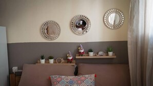 A bedroom with a bed, decorative mirrors, and shelves with plants and figurines. - Cosy and Large Studio in Heraklion Crete, Greece (Heraklion)