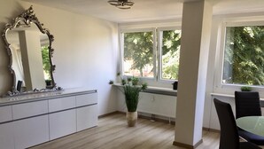Una cocina moderna con un armario blanco, un espejo grande y una ventana con vistas a árboles.