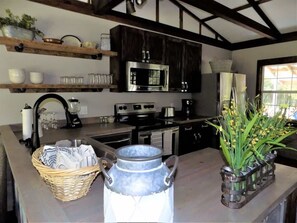 A kitchen with a microwave, stove, and various kitchen items on shelves.