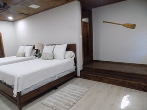 Ein Schlafzimmer mit zwei Betten, einem Holz-Kopfteil, einer weißen Wand und einem Holzboden.