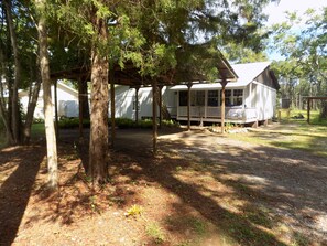 Eine Hütte mit Veranda, umgeben von Bäumen und einem überdachten Bereich.
