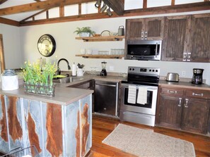 Une cuisine avec des meubles en bois, des appareils électroménagers en acier inoxydable et un îlot central au style rustique.