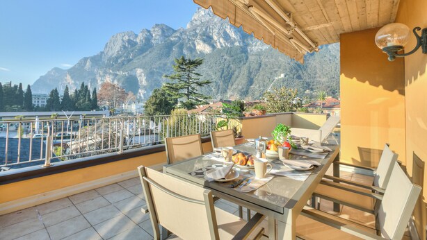 Ein Balkon mit Tisch für zwei Personen, mit Blick auf eine gebirgige Landschaft.