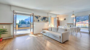 Ein großzügiger Wohnbereich mit einer Couch, einem kleinen Tisch und Blick auf die Stadt durch große Fenster.