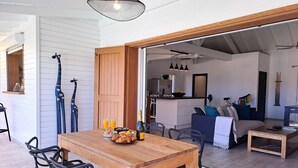 A dining area with a wooden table, black chairs, and a breakfast setting including croissants and fruit. - Villa Moringa Vue Mer - 5 mn Orient Bay or Grand Case (ST MARTIN)