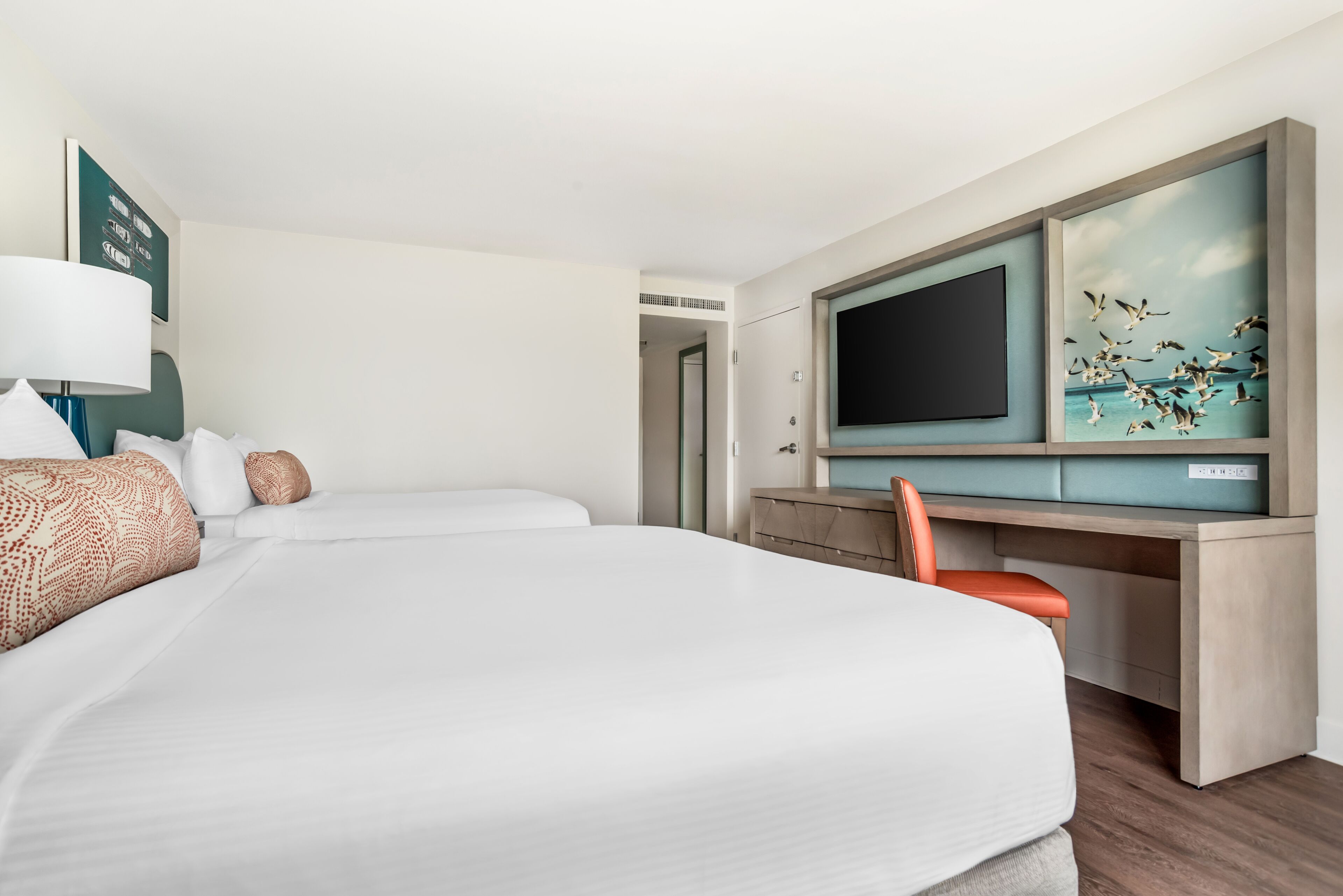 Une chambre d’hôtel avec un grand lit, un bureau doté d’une télévision à écran plat et une vue sur la mer.