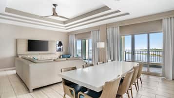 Een moderne hotelkamer met een ruime eettafel, een bank, een flatscreen televisie en een balkon met uitzicht op het water.