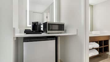 Una kitchenette compacta equipada con microondas, cafetera y lavavajillas.