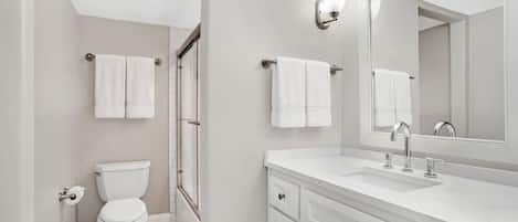 Een moderne badkamer met toilet, douche en wastafel.