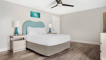 A bedroom with a bed, nightstands, a ceiling fan, a door, and a wall-mounted picture.
