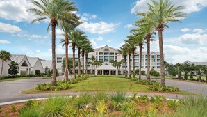 A hotel with a central lawn, palm trees, and a multi-story building with a flat roof. - Hilton Vacation Club Bayside Resort Panama City Beach (Panama City Beach)