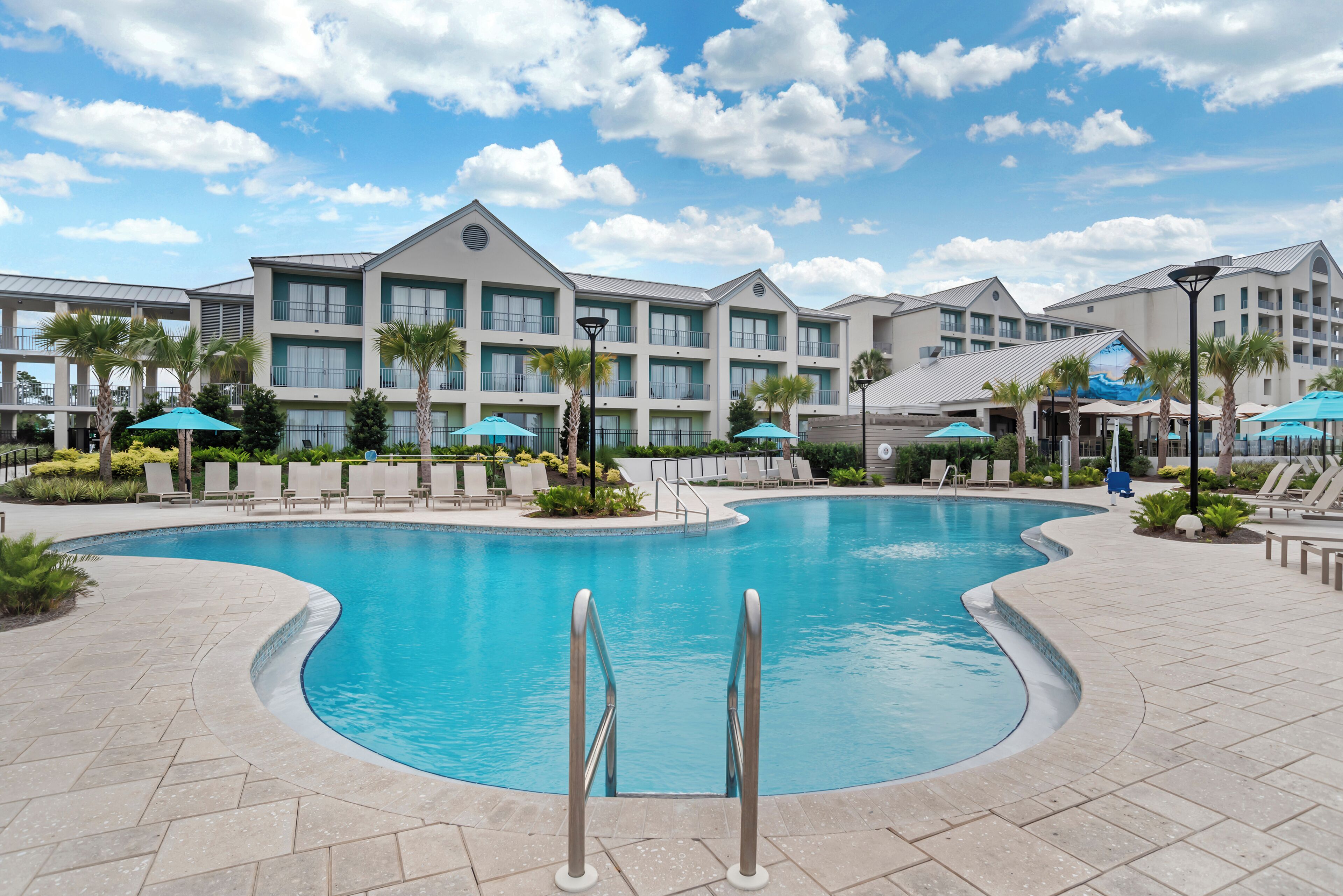 A hotel with a swimming pool, lounge chairs, and a landscaped garden.