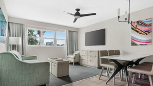 A modern hotel room with a sofa, a dining table, a TV, and a ceiling fan. - Hilton Vacation Club Bayside Resort Panama City Beach (Panama City Beach)