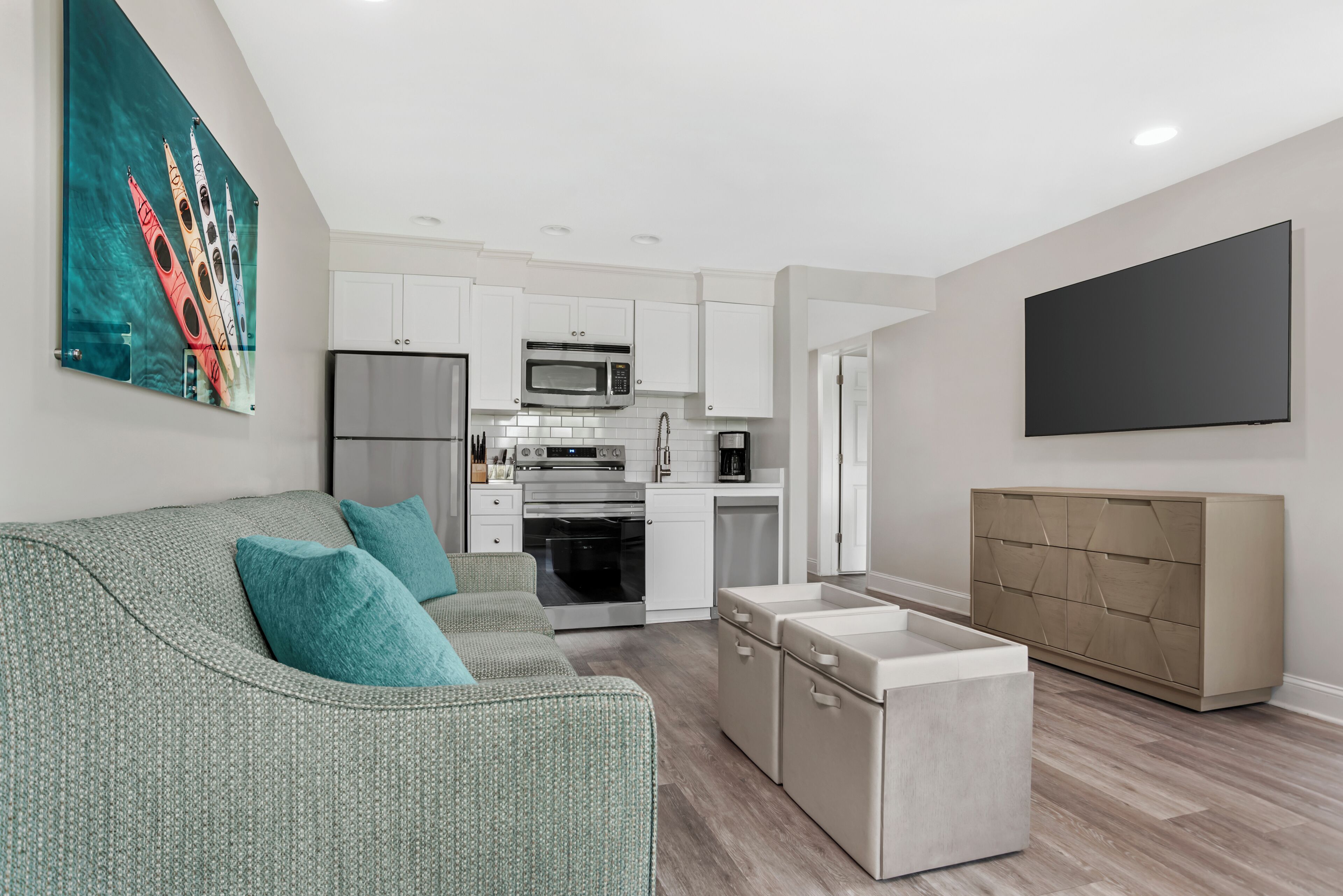 Un salon moderne avec un canapé gris, des coussins turquoise, un téléviseur à écran plat et une table basse au design minimaliste.