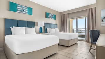 Quarto de hotel com duas camas, uma escrivaninha, uma cadeira e varanda com vista.