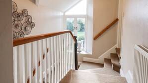 A staircase with white railings and a view of a garden outside.