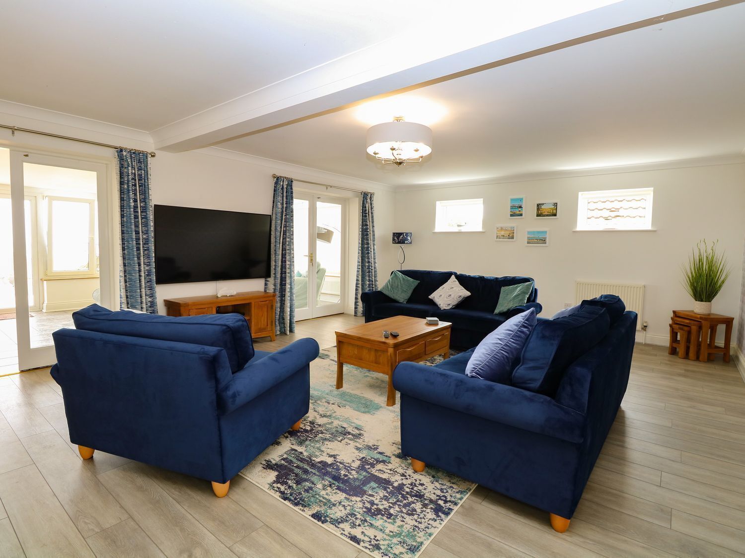 A living room with two blue sofas, a coffee table, a TV, and a chandelier.