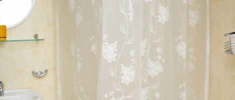A bathroom with a white sink, a mirror, and a shower curtain with a floral pattern.