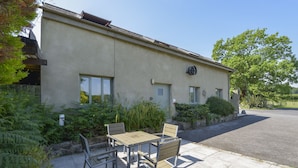 A building with a patio area featuring a table and chairs. - Oak Leaves Cottage (Newton Abbot)
