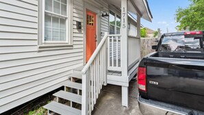A house with a porch, a red door, and a black pickup truck parked outside. - 3 Bedroom Home in the Heart of New Orleans! (New Orleans)