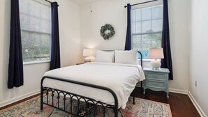 A bedroom with a bed, two bedside tables with lamps, a rug, and a wall-mounted wreath. - 3 Bedroom Home in the Heart of New Orleans! (New Orleans)