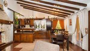 A cozy kitchen with wooden cabinets, a stone fireplace, and a dining area with a table and chairs.
