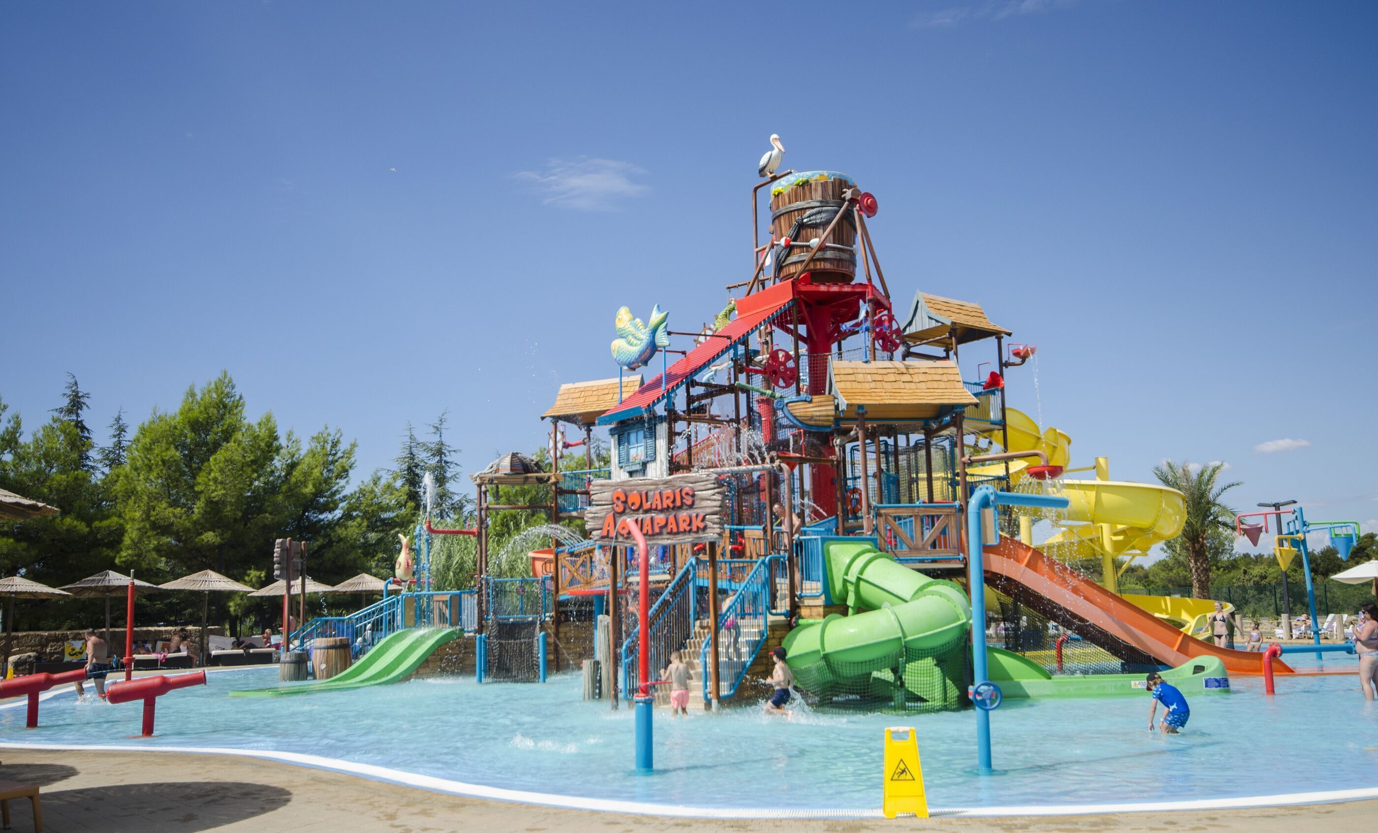 Un parque acuático con un tobogán gigante, una piscina de olas y un cartel que dice 'Solaris Aquapark'.