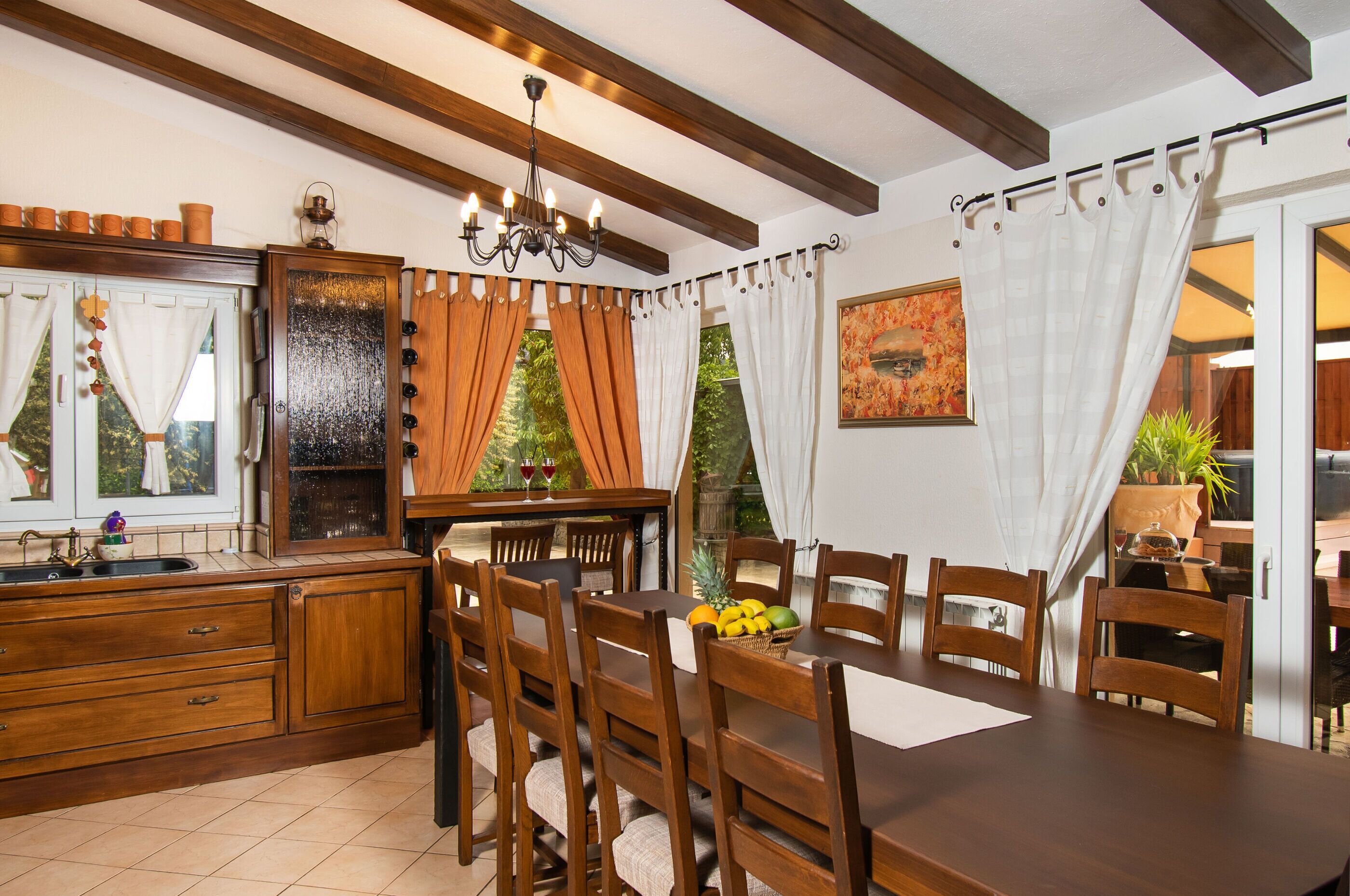 A dining area with wooden furniture, a chandelier, and a view of the outdoors.