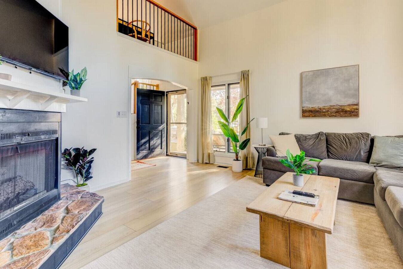 A spacious living room with a fireplace, a sofa, a coffee table, and a painting on the wall.